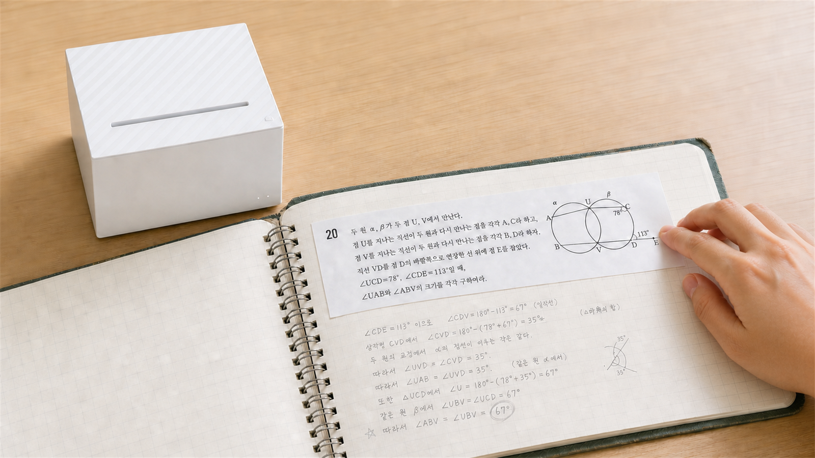 가로로 긴 수학 문제 라벨을 손으로 노트에 붙이는 장면과 옆에 놓인 네모닉 MIP-201
